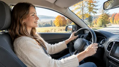 Entspannte Autofahrerin auf einer sonnigen Landstraße mit Herbstlaub